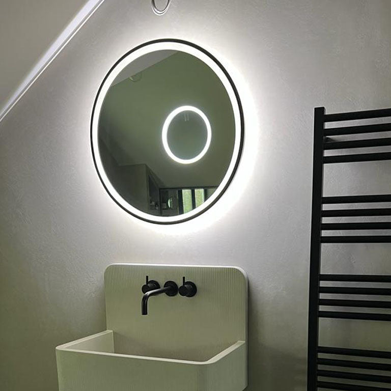 Edge-lit bathroom mirror with black metal frame and magnification mirror